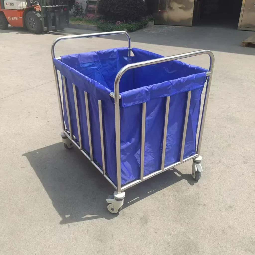 Industrial metal-framed laundry cart with a blue fabric liner and wheels on a concrete surface.