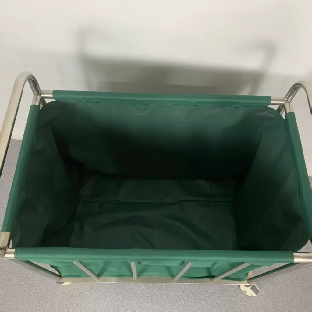 Top view of an empty green linen cart with a fabric liner and metal frame on a tiled floor.
