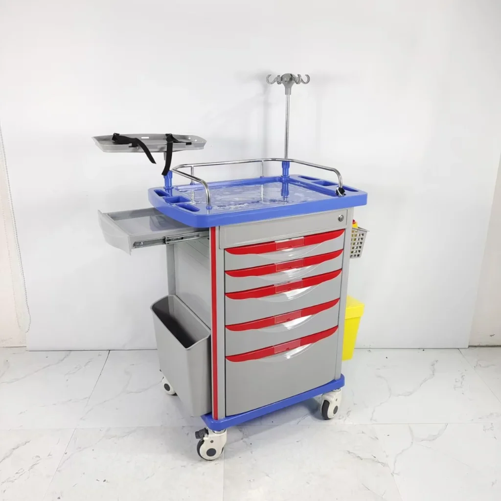 Hospital emergency medical trolley with multiple red drawers, an IV pole, and side storage, on a white floor.