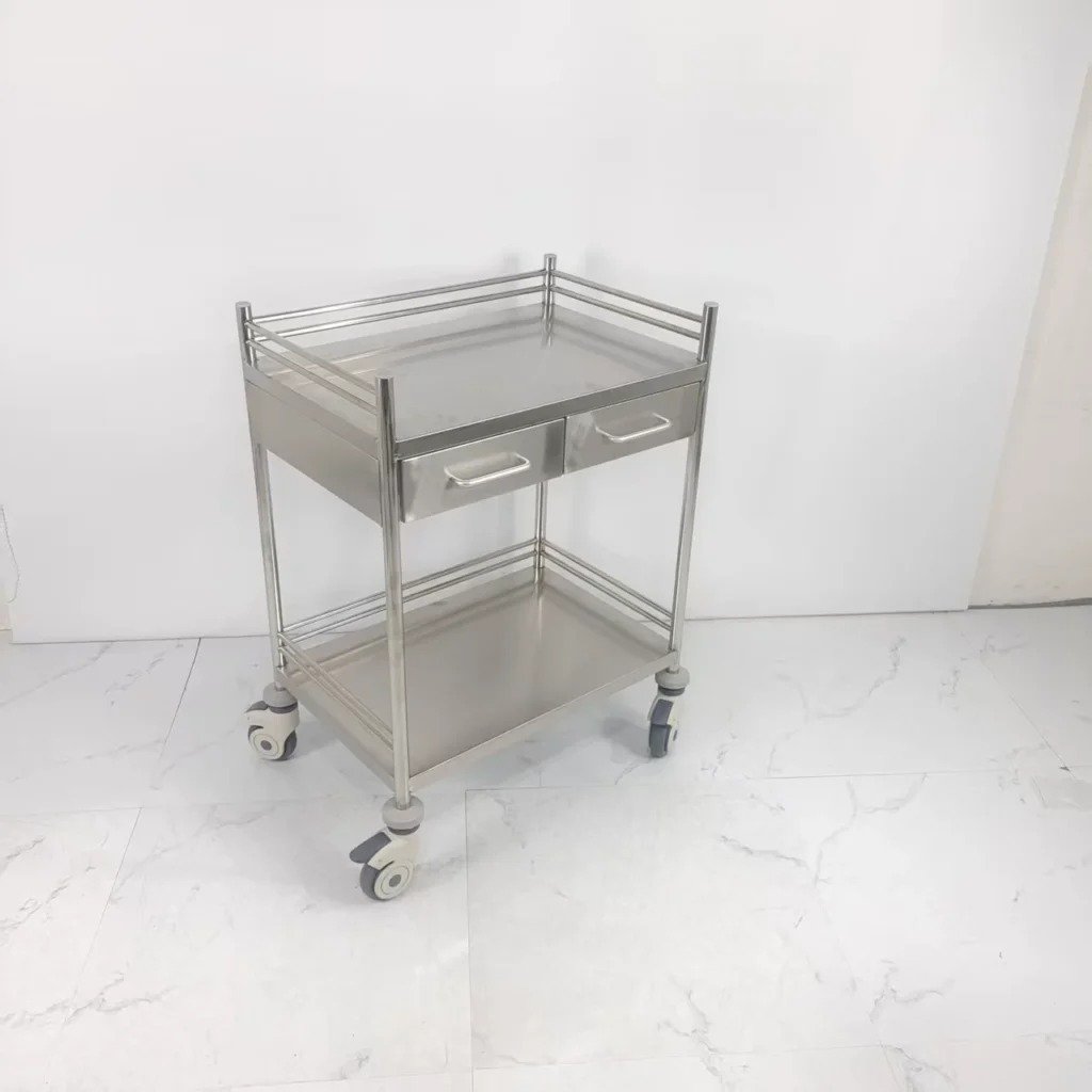Stainless steel medical trolley with two shelves and four wheels in a bright room.