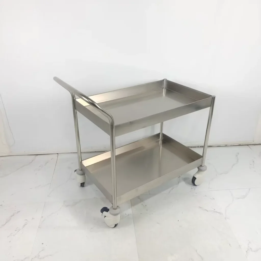 Stainless steel trolley with two shelves and four casters on a white tiled floor.