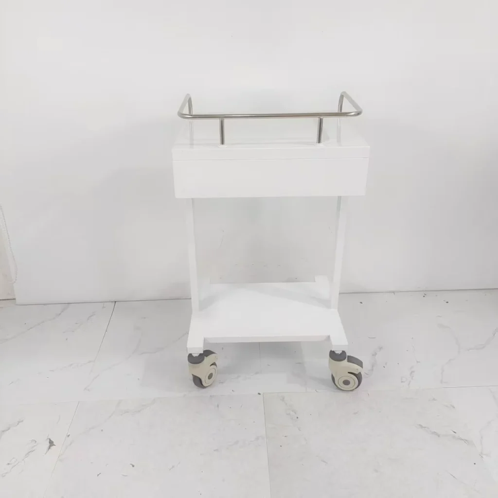 White metal trolley with a stainless steel rail and four wheels on a tiled floor.