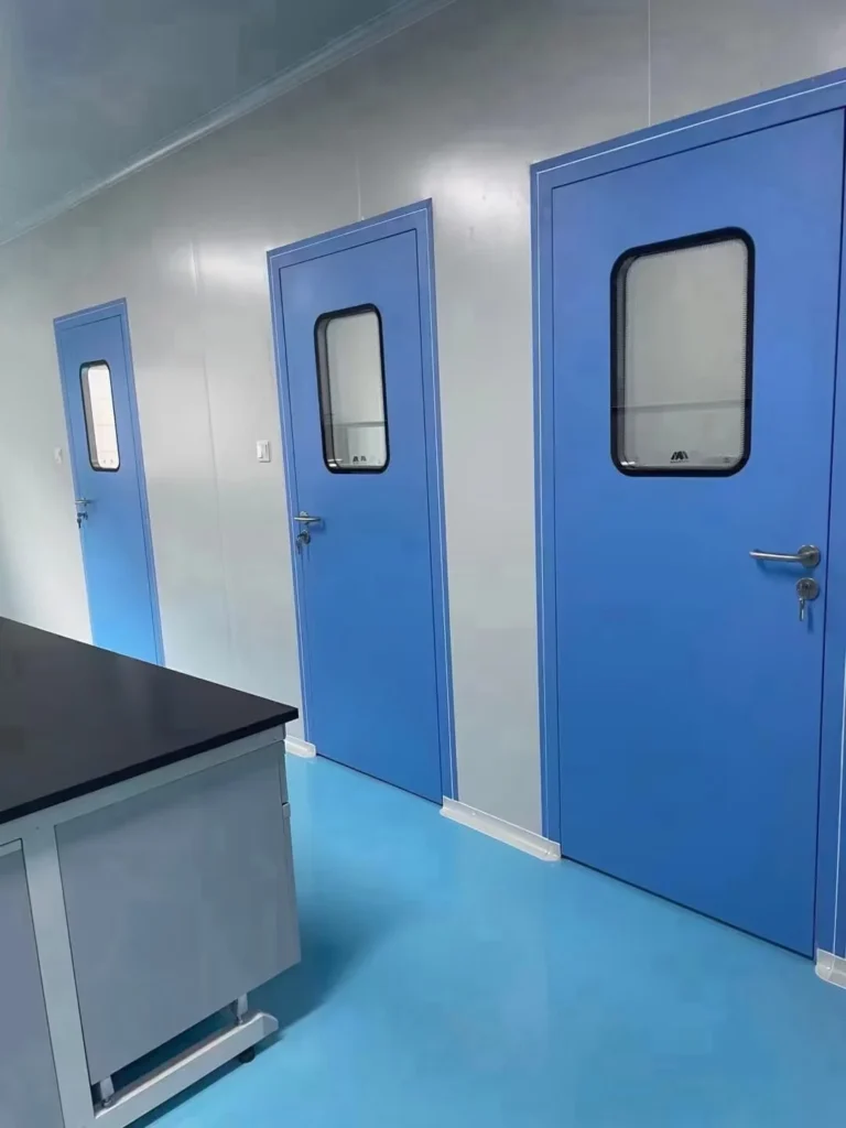 Interior view of a cleanroom with blue doors and a laboratory bench, emphasizing a sterile environment.