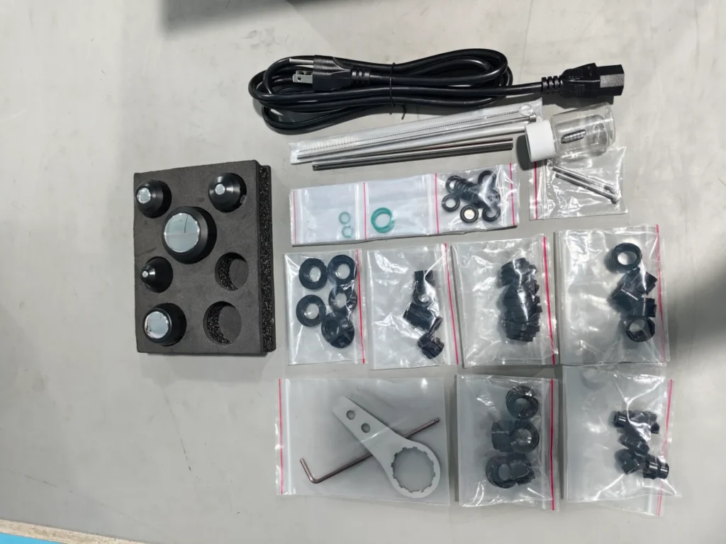 A set of electronic components and accessories including a power cable, connectors, and various small parts organized on a table.