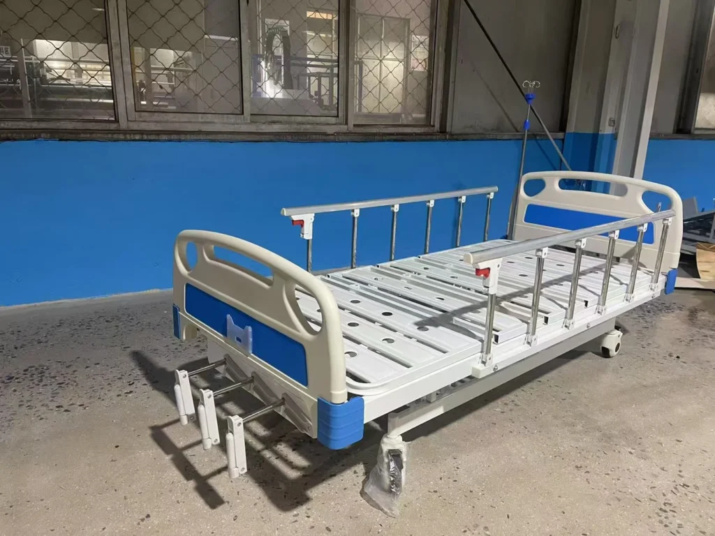 A hospital bed with blue and white accents, positioned in a warehouse with blue walls and large windows.