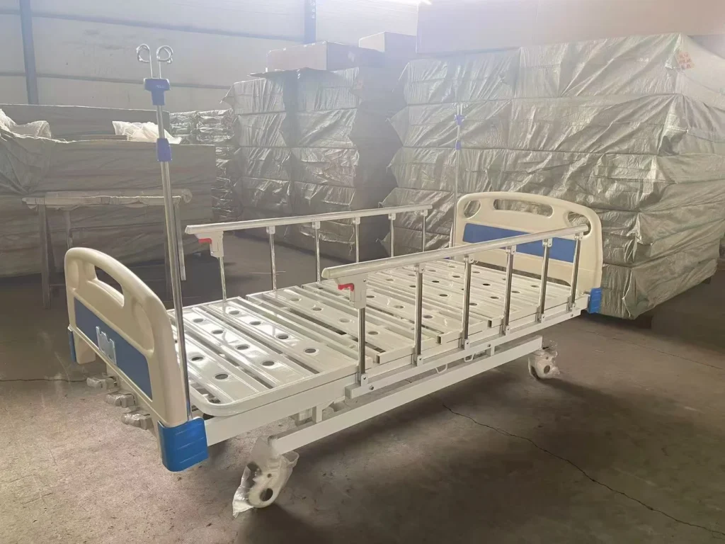 Metal hospital bed with rails in a storage facility, surrounded by stacked, covered crates and boxes.