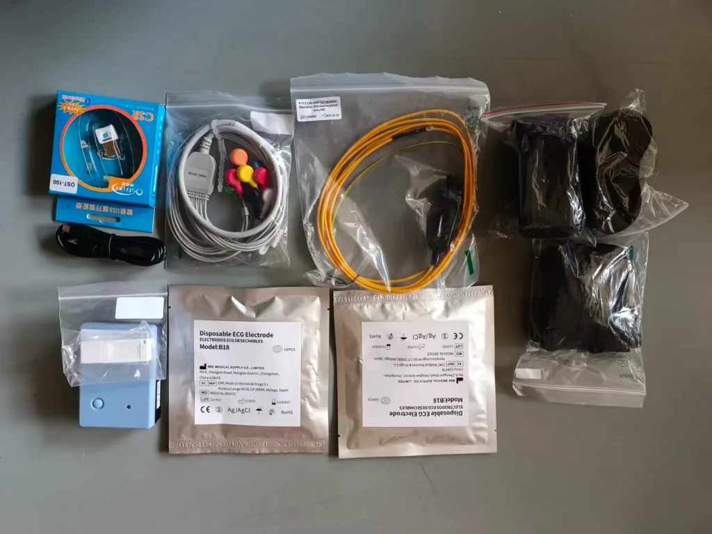 Various medical monitoring accessories including ECG electrodes, cables, and other components arranged on a surface.