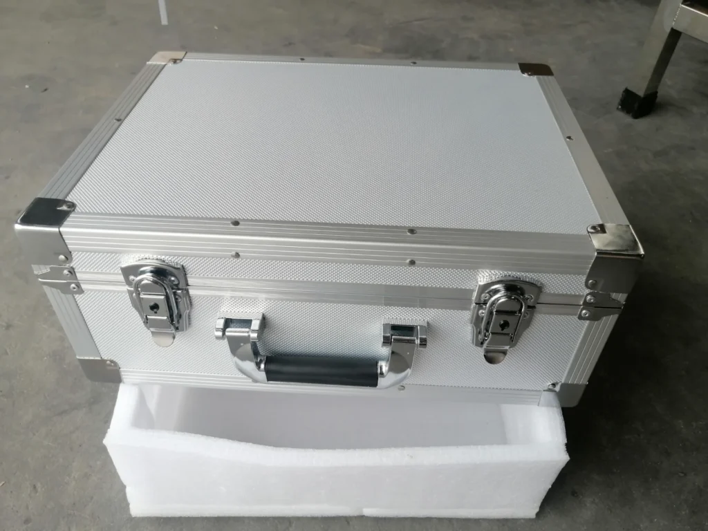 Metallic storage case with secure locks and handle, placed on a styrofoam base.
