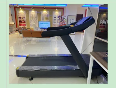 A modern treadmill positioned in a showroom, surrounded by informational displays and comfortable seating.