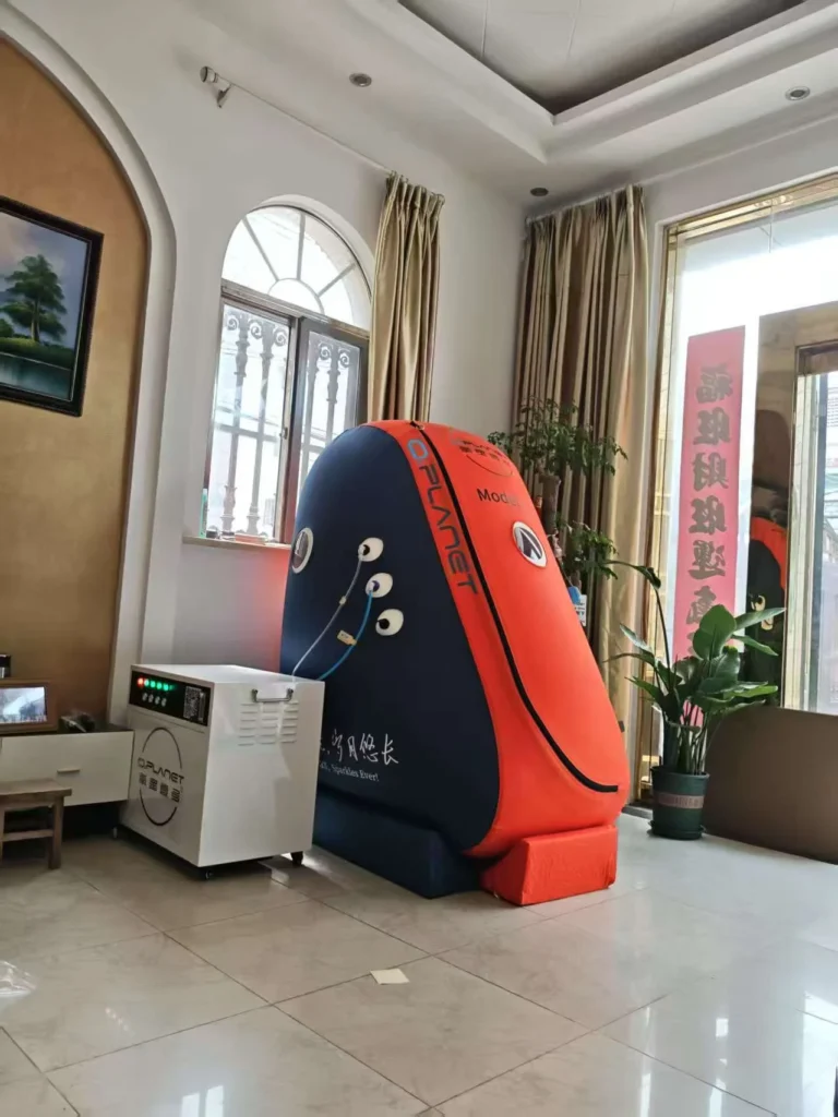 Orange and blue hyperbaric chamber in a room with nearby control unit and potted plants.