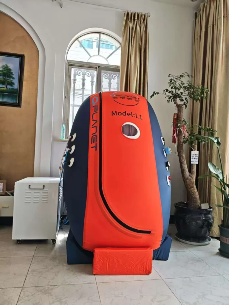 Orange and blue hyperbaric chamber with labeled 'Model: L1' positioned indoors near a large window and plants.