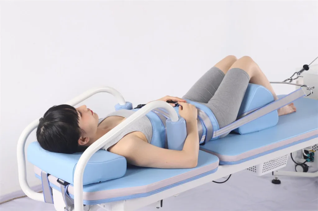 A woman lying on a decompression machine with blue padding, wearing comfortable workout attire, during a physical therapy session.