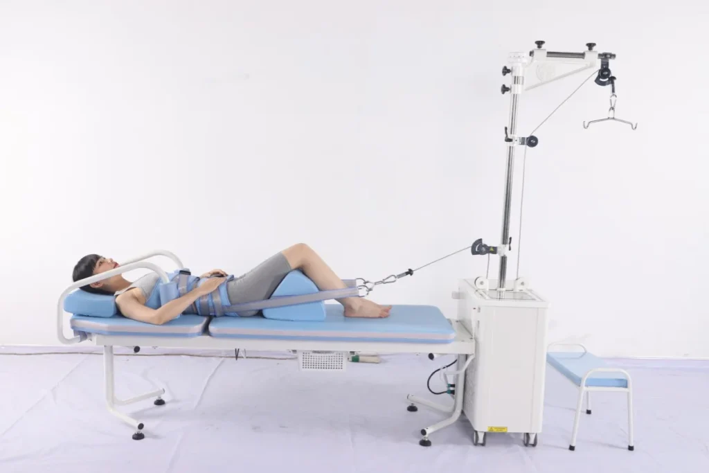 Woman lying on a physical therapy table using exercise equipment for rehabilitation. She's secured with straps and a pulley system.
