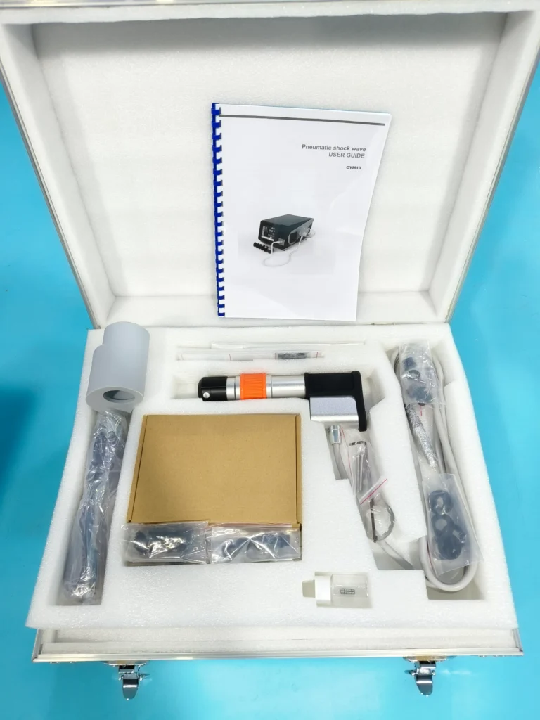 Open case showing a pneumatic shock wave therapy kit with user guide, various parts, and accessories neatly arranged.