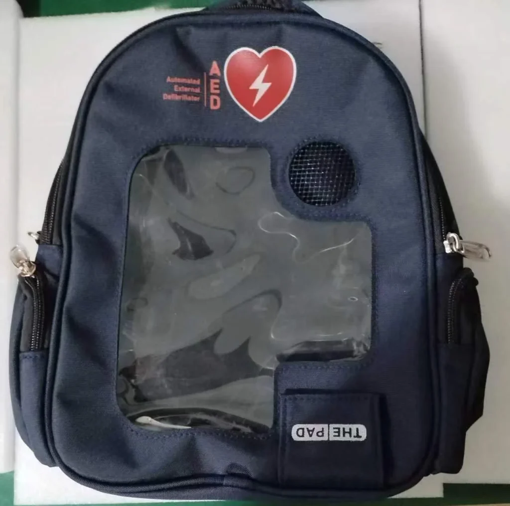 Blue Automated External Defibrillator (AED) carrying case with a transparent window and labeled sections for storage.