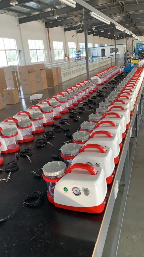 Rows of red and white vacuum devices with cables aligned on an assembly line in a factory setting.
