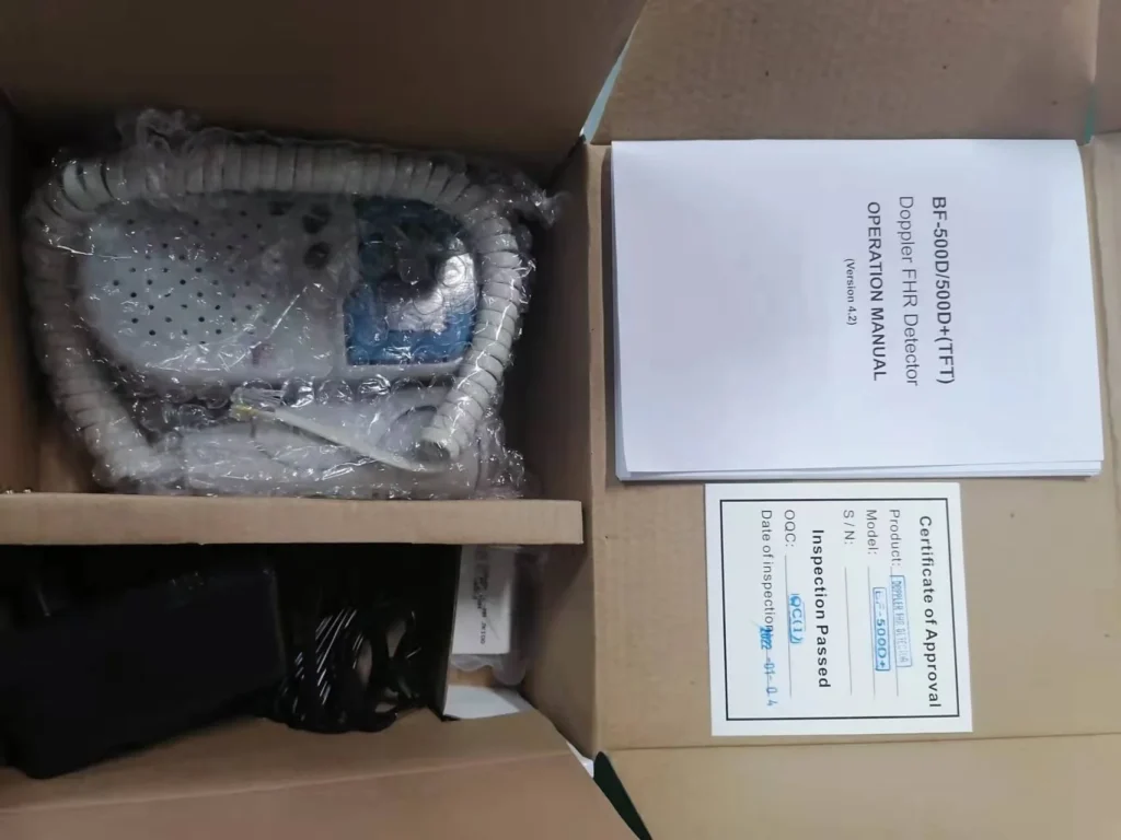 Box containing a Doppler FHR detector with coiled cord, operation manual, and certificate of approval, organized neatly.