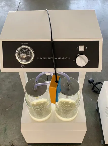 Electric suction apparatus with dual glass jars, pressure gauge, and control knob, used for medical or laboratory purposes.