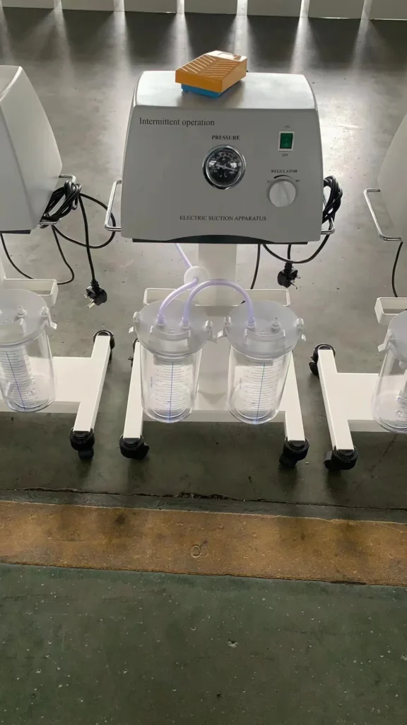 Electric suction apparatus with dual transparent collection jars on wheels, featuring a control panel with pressure and regulator settings.