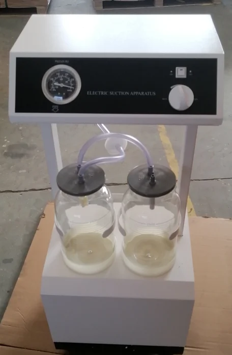 Electric suction apparatus featuring dual glass jars, control panel, and tubing, placed in an industrial setting.