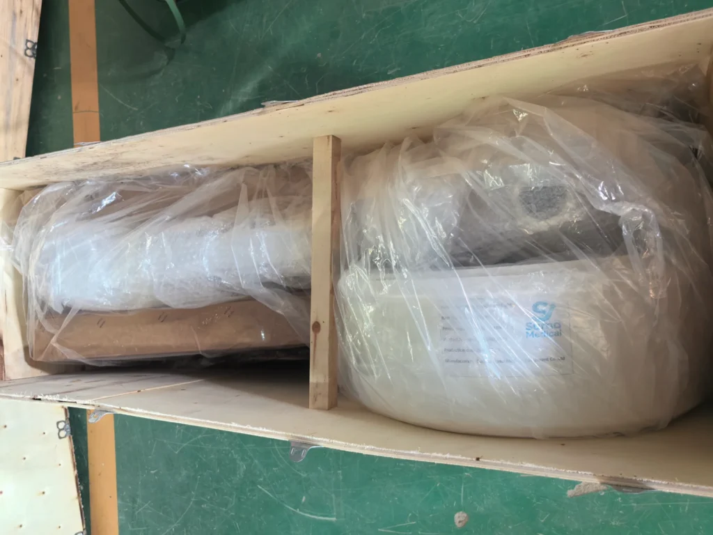 Medical device securely packaged in plastic and foam inside a wooden crate with protective layers.