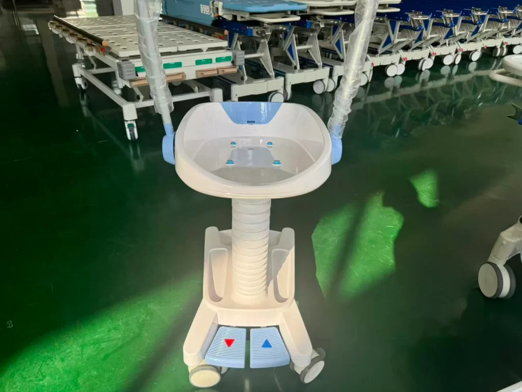 A white medical patient transport cart with a basin and adjustable features, placed on a green floor in a hospital equipment storage area.