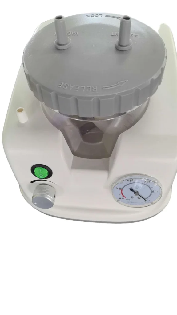 Close-up of a medical vacuum pump machine featuring a gray lid with labeled ports, a pressure gauge, a green power button, and a control knob.
