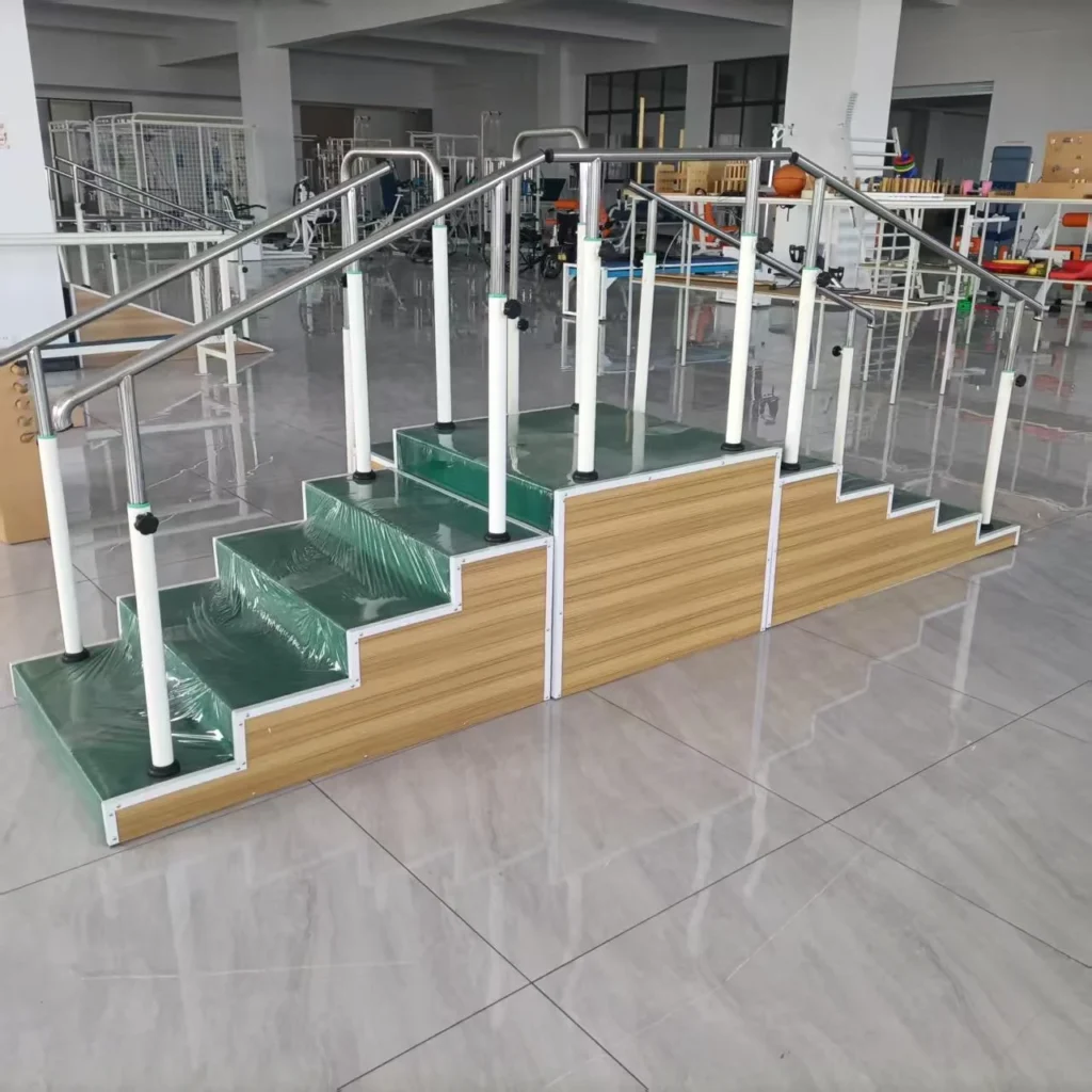 Rehabilitation training stairs with green steps, metallic handrails, and a wooden base, located in a medical facility.