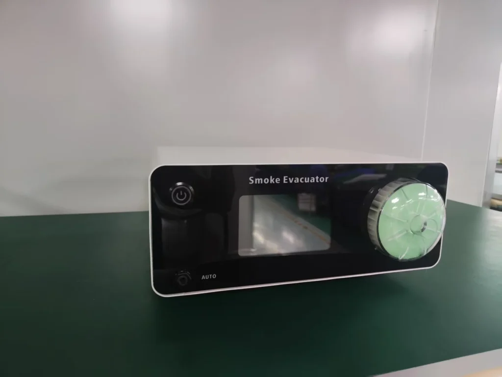 Smoke evacuator device with a black front panel, power button, and dial, placed on a green table in a minimal workspace.