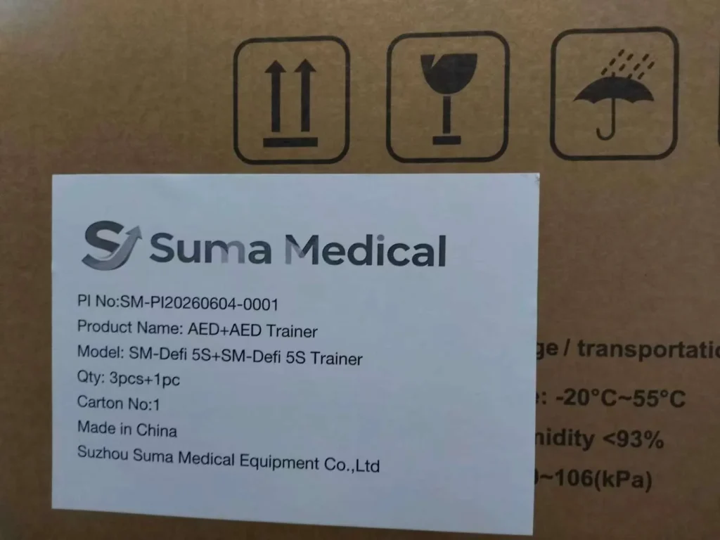 Close-up view of Suma Medical packaging with a label featuring product details about an AED Trainer and shipping symbols on the box.