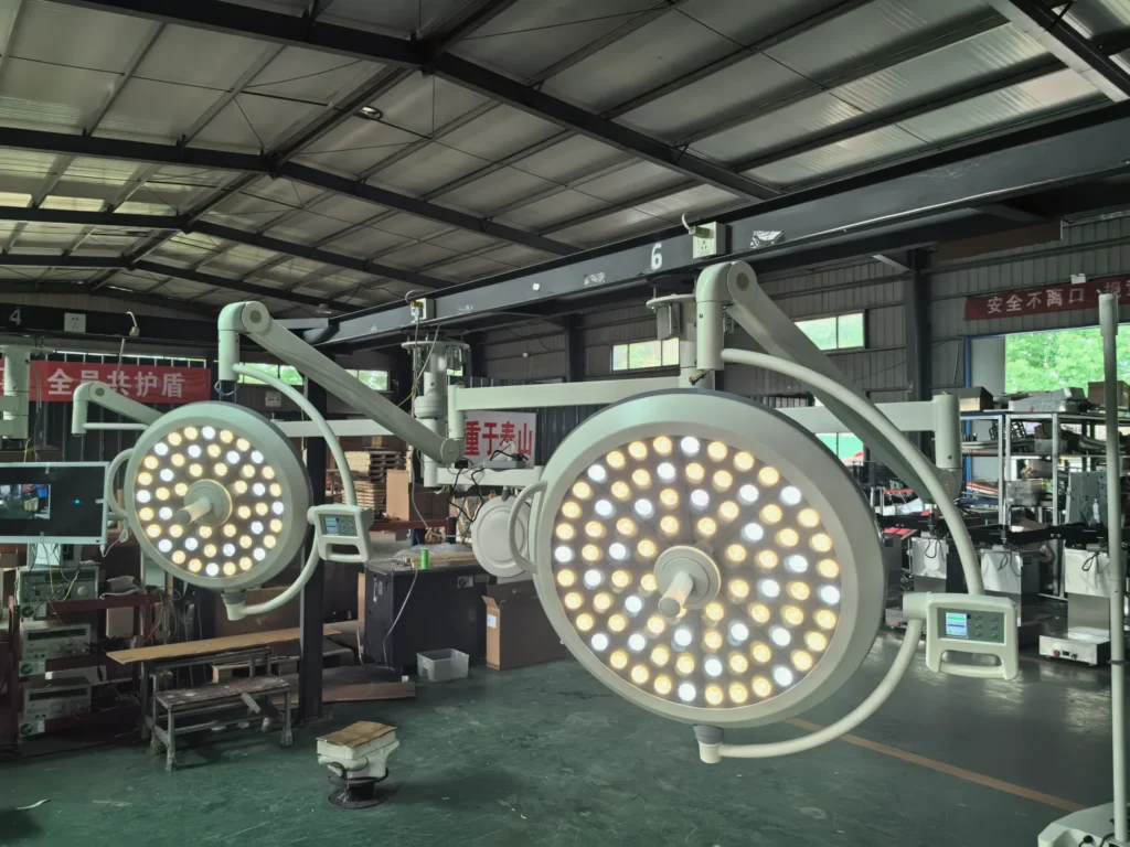 Two large surgical ceiling lights with LED panels in a manufacturing facility. Overhead fixtures and industrial setup visible.
