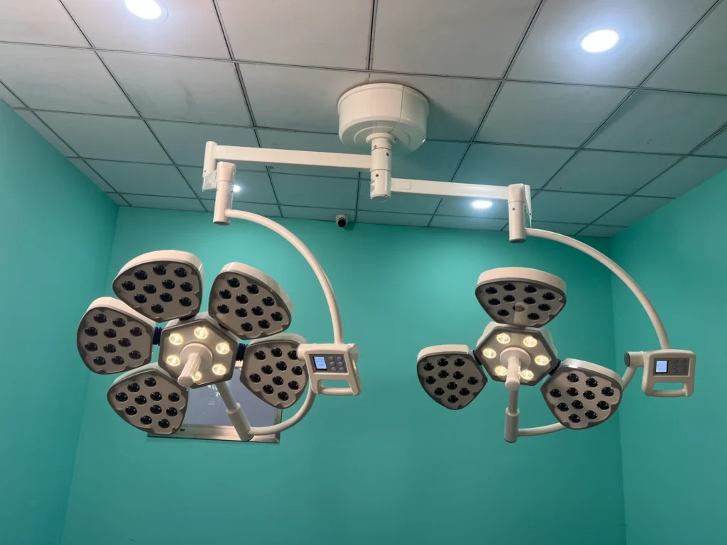 Modern surgical ceiling lights with LED panels mounted on the ceiling of a teal-colored medical room.