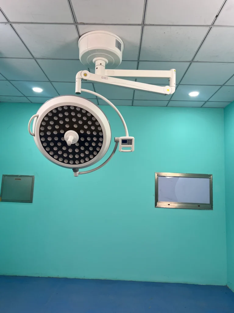 Ceiling-mounted surgical light with multiple LED bulbs in a green-walled operating room.