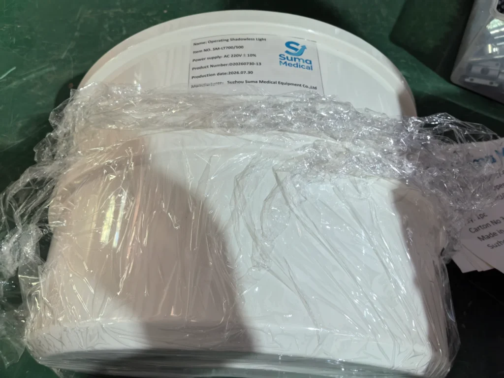 Packaged white surgical operating shadowless light from Suma Medical, wrapped in clear plastic, placed on a dark surface.