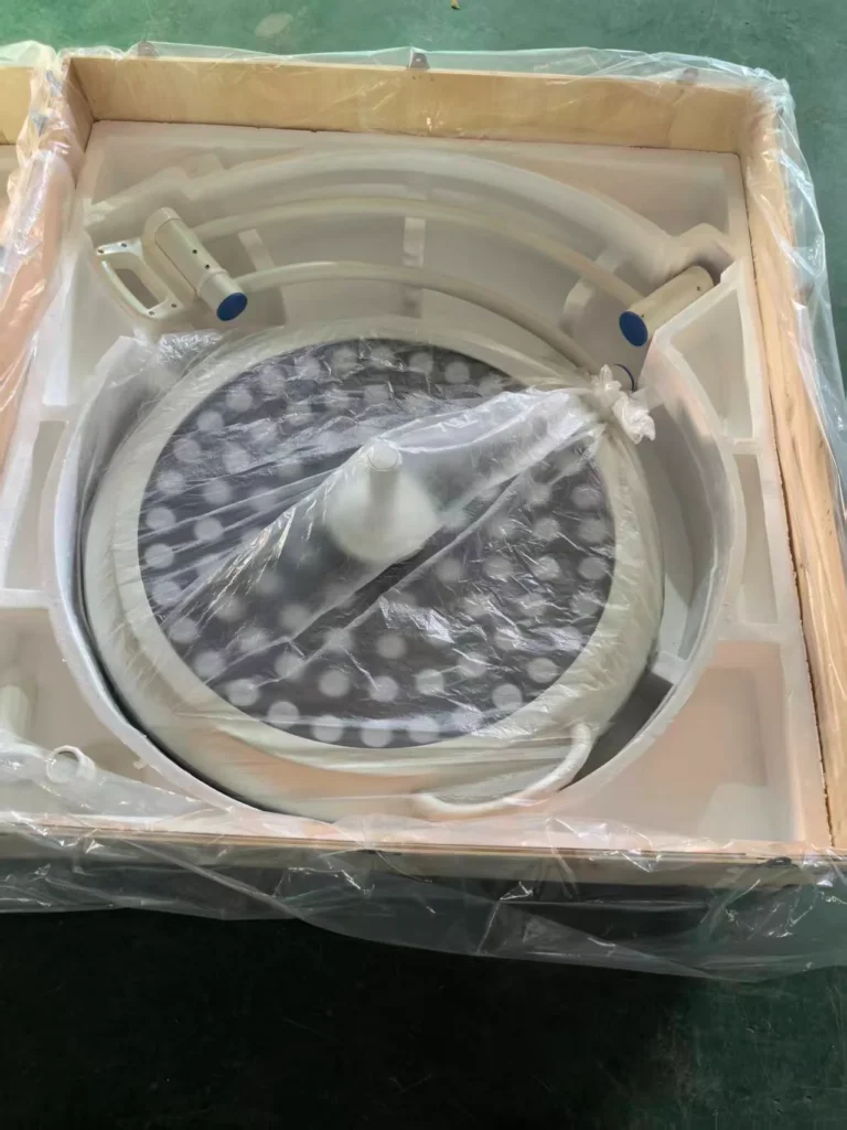 Surgical operating light partially assembled and secured in a wooden shipping crate with protective plastic wrapping.