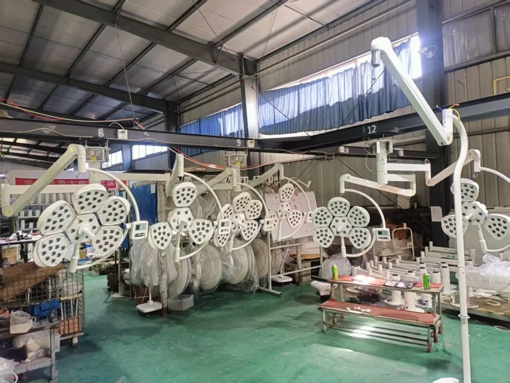 Multiple surgical lights in various stages of assembly in a manufacturing facility with industrial interior.