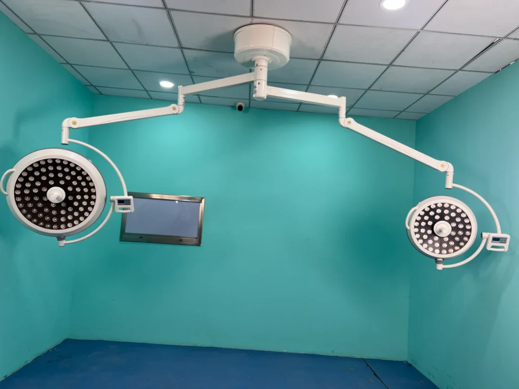 Ceiling-mounted surgical operating lights with LED bulbs in a sterile hospital room with blue walls and ceiling tiles.