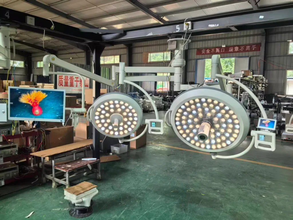 Two surgical operating lights with LED panels in a manufacturing workshop, surrounded by machinery and equipment.