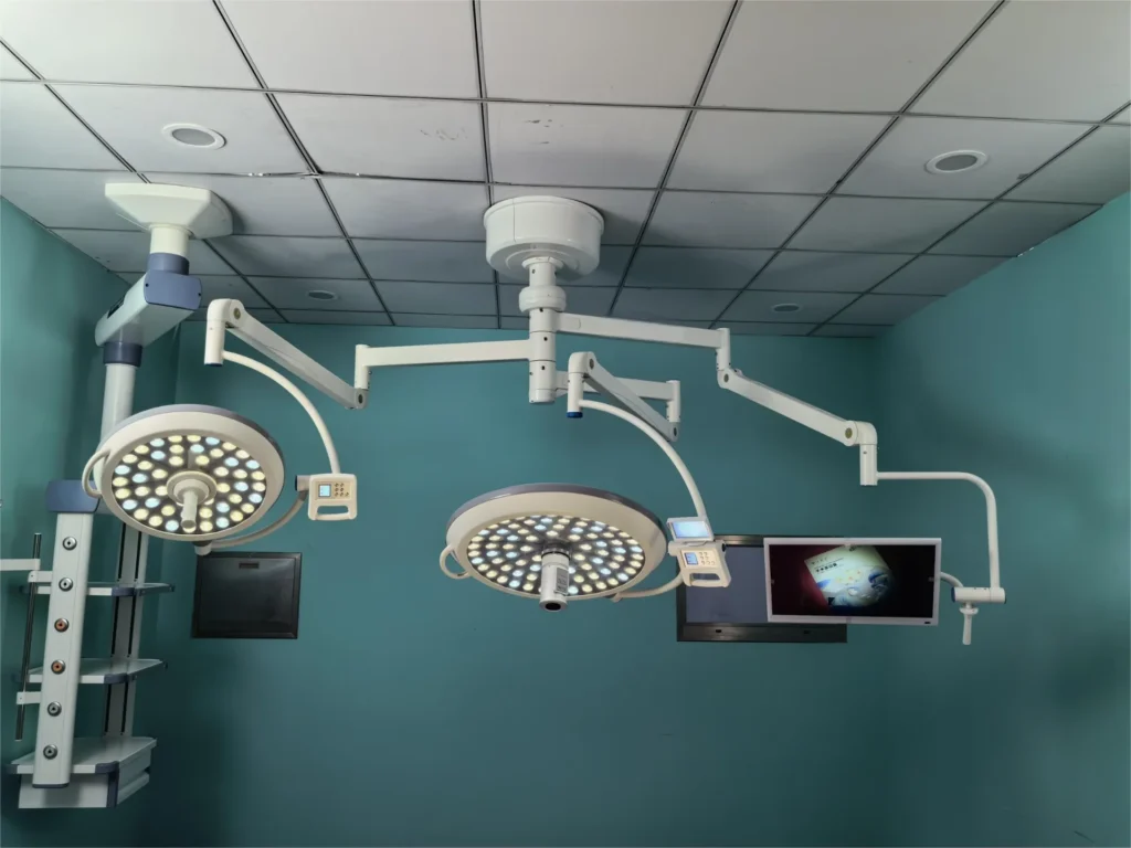 Ceiling-mounted surgical operating room lights with LED panels and monitors in a sterile medical environment.