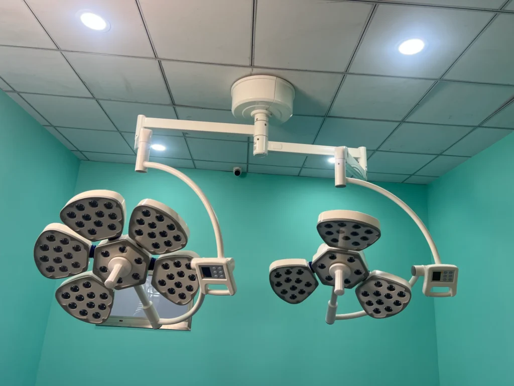 Ceiling-mounted surgical operating room lights with multiple LED panels in a well-lit turquoise room.