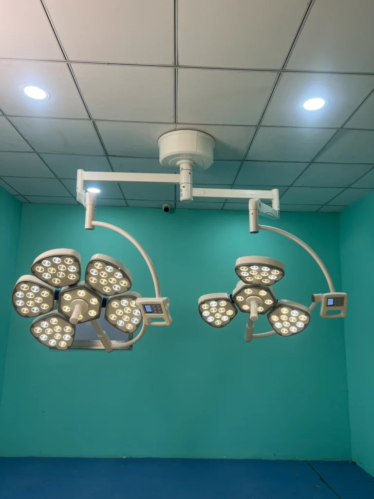 Ceiling-mounted modern surgical lights with multiple LED panels in a teal-painted operating room.