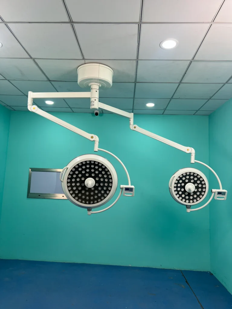 Ceiling-mounted surgical operating room lights with LED panels in a sterile teal-colored operating room environment.
