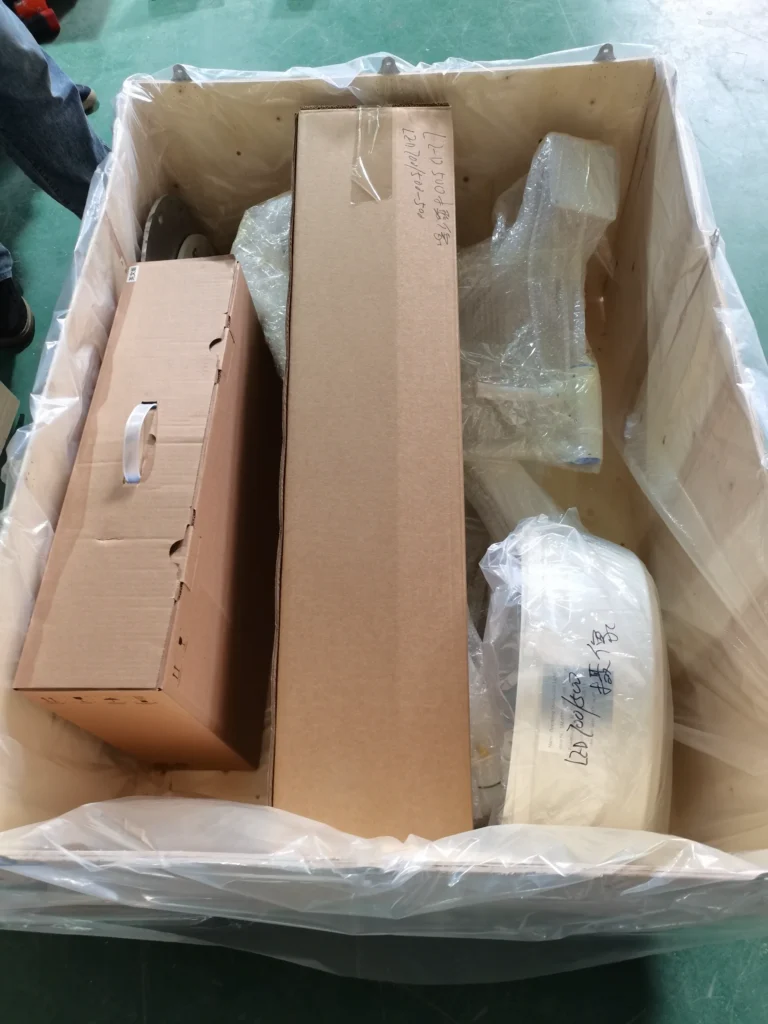 Open wooden crate containing various packaged items, including cardboard boxes and wrapped materials, ready for shipping.