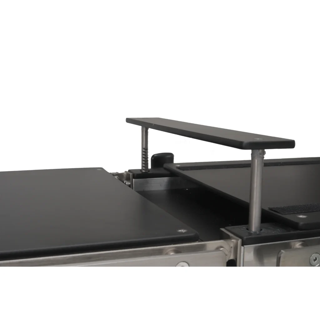 A close-up view of an adjustable exercise reformer bar with a sleek black surface and metal supports on a fitness apparatus.