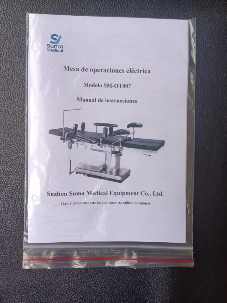 Instruction manual for Suma Medical electric operation table model SM-OT007, sealed in plastic bag, placed on a dark surface.